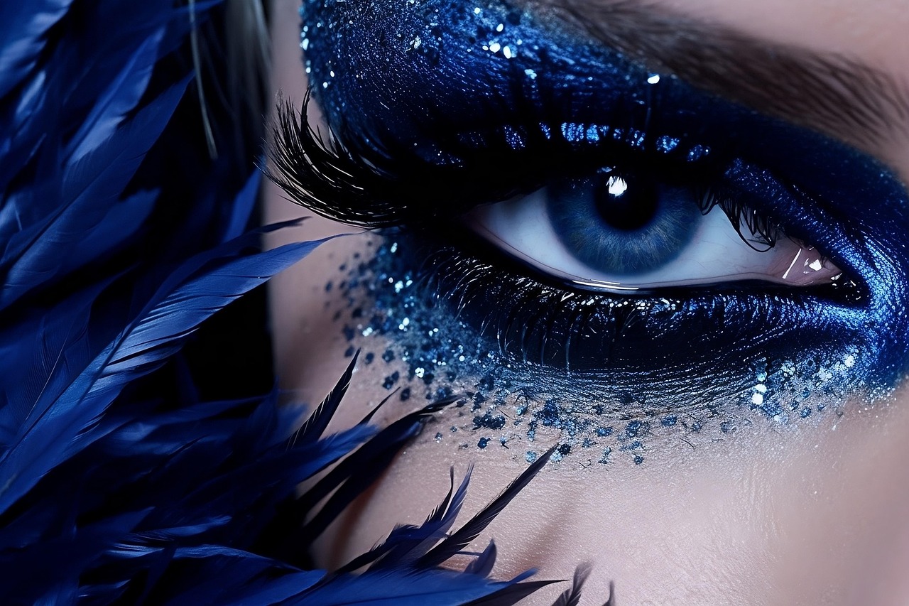 Detailný záber na oko s modrou maskarou a trblietkami.