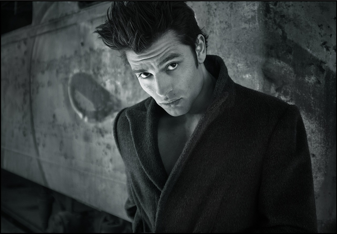 Čiernobiela fotografia muža v kabáte.