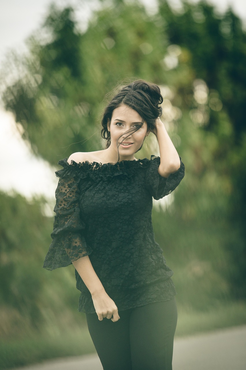 Žena v čiernom tope s odhalenými ramenami a zlatými náušnicami.