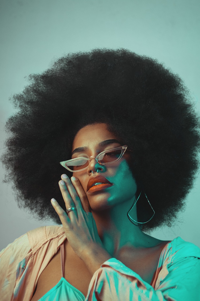 Portrét ženy s afro účesom a opálenou pokožkou, vhodný na ilustráciu samoopaľovacích produktov.